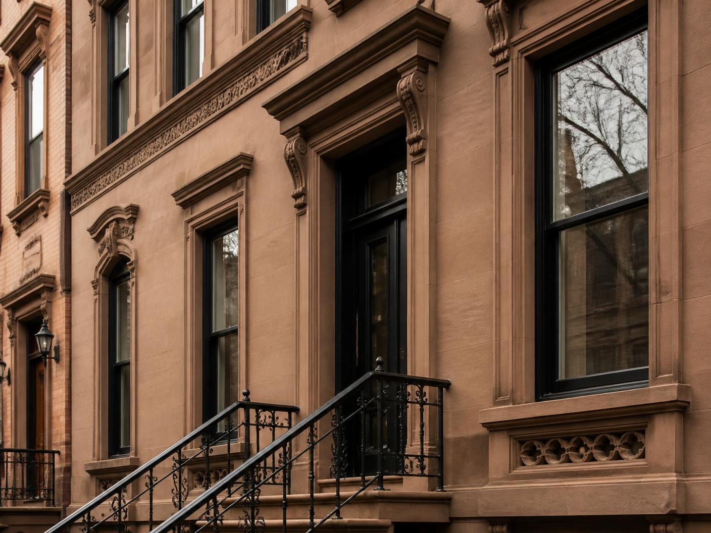 Restored brownstone facade with repointed masonry, carved stone lintels and ironwork
