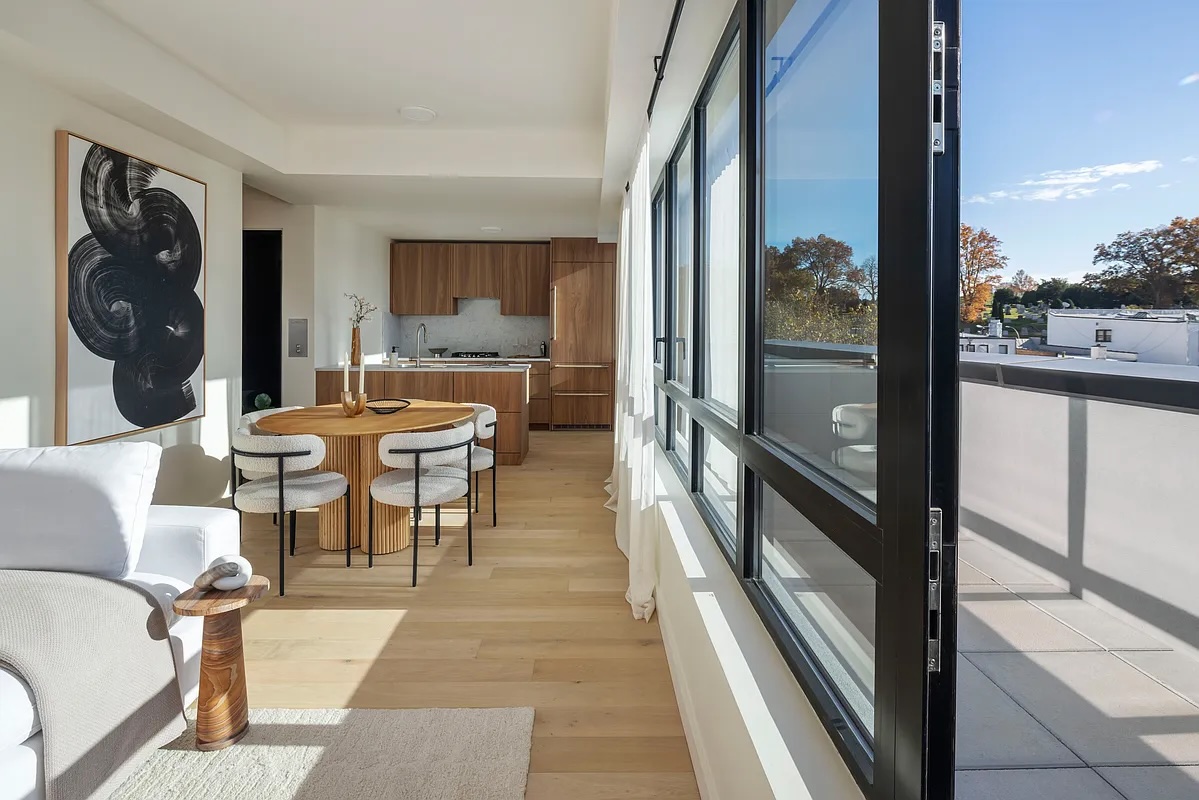 Greenwood Heights — narrow rooftop terrace with pale stone pavers alongside black-framed windows and a clear sky — image 9 of 16