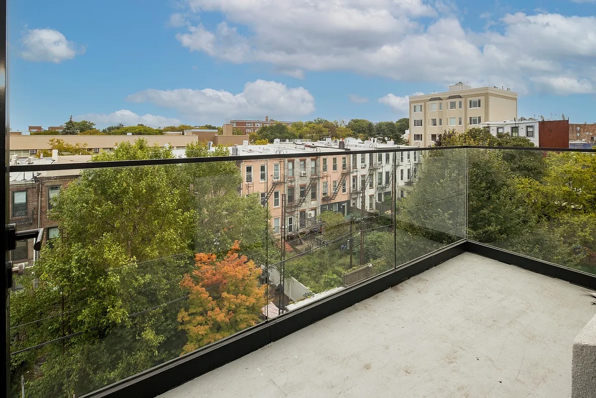 Greenwood Heights — narrow rooftop terrace with pale stone pavers alongside black-framed windows and a clear sky — image 10 of 16
