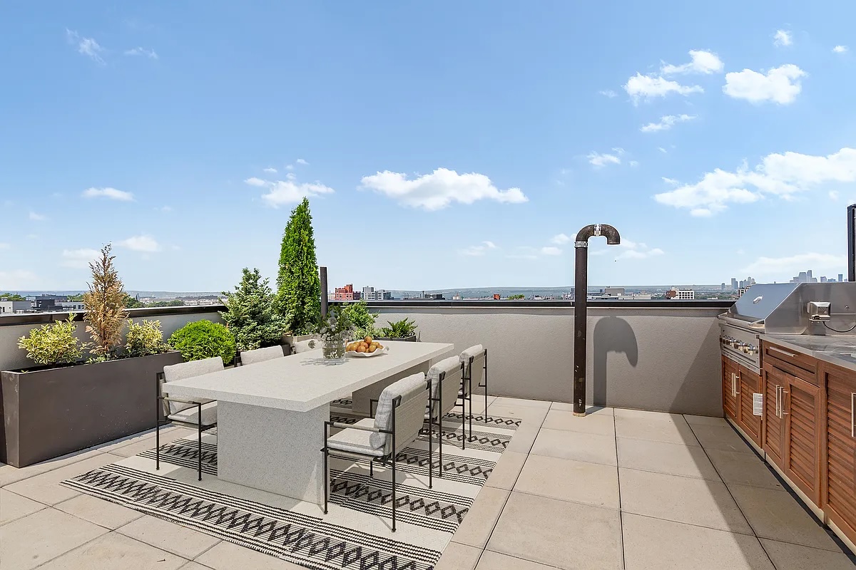 Greenwood Heights — narrow rooftop terrace with pale stone pavers alongside black-framed windows and a clear sky — image 3 of 16