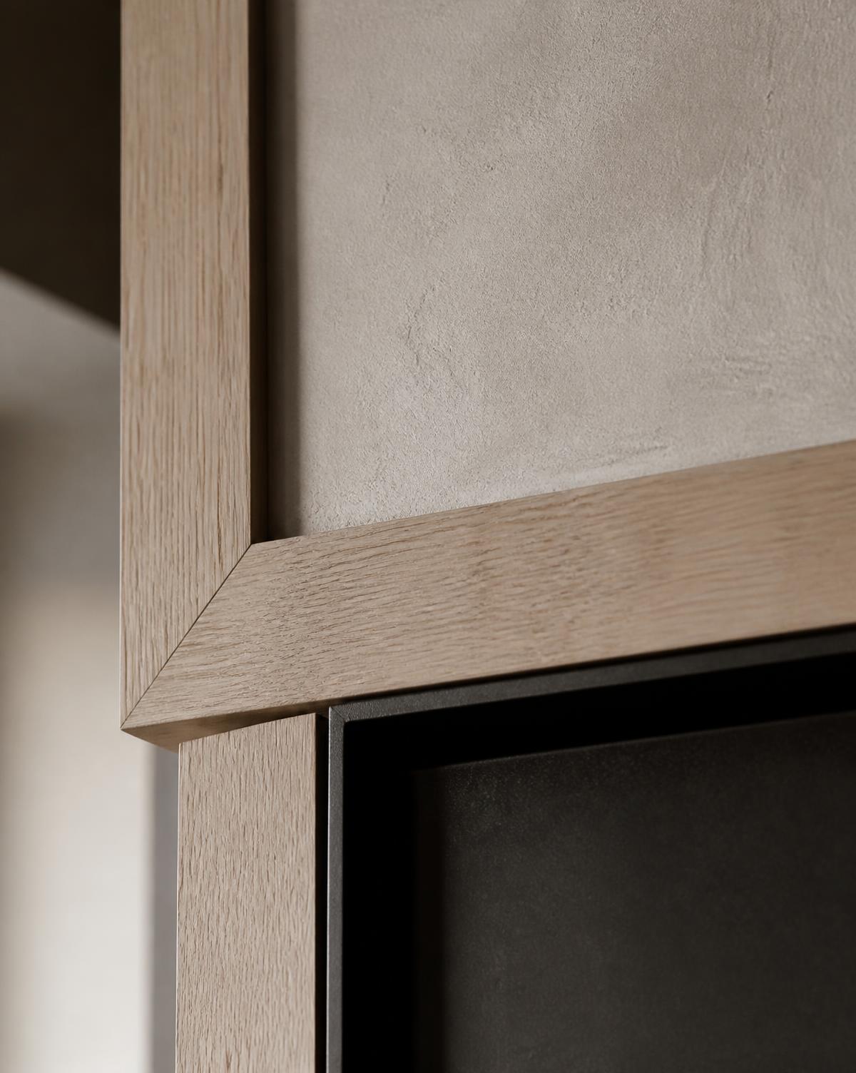 Mitered white oak millwork meeting hand-troweled plaster with a blackened steel reveal